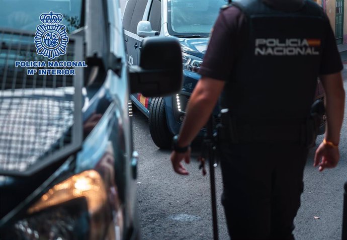 Imagen de archivo de un agente de la Policía Nacional junto a varios vehículos policiales