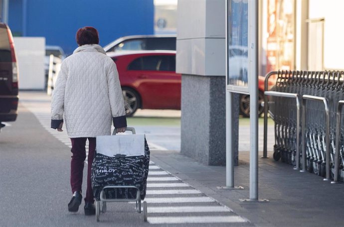 Una mujer sale de un supermercado con un carro de la compra, a 27 de diciembre de 2022, en Mejorada del Campo, Madrid (España).