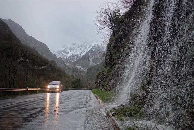 Un coche circula por una carretera mojada a causa de la nieve, a 18 de enero de 2023, en Ponga, Asturias (España). La Agencia Estatal de Meteorología (Aemet) ha elevado a naranja el nivel de alarma en Asturias, tanto por fenómenos costeros, como por acu