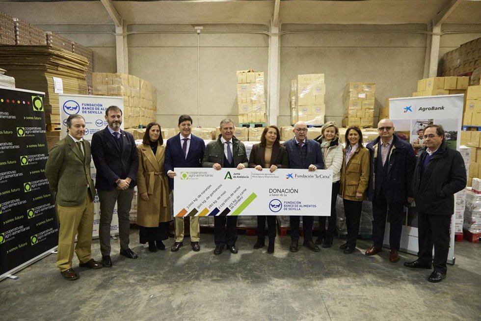 La consejera de Agricultura, Agua y Desarrollo Rural de la Junta de Andalucía, Carmen Crespo, (c) posa con el cohete de la donación durante la entrega una donación de productos al Banco de Alimentos de Sevilla