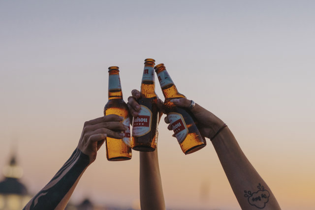 Personas brindando con Mahou