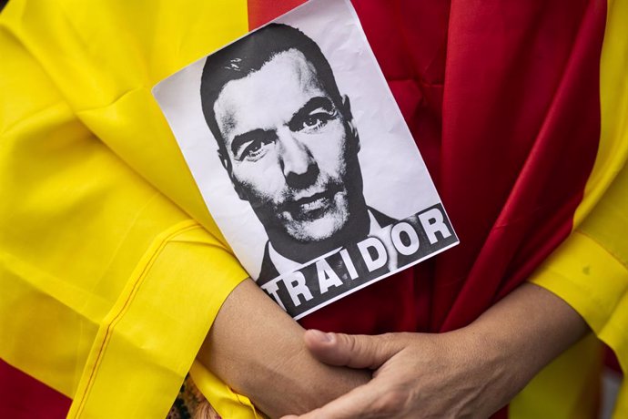 Archivo - Un home vestit amb la bandera d'Espanya subjecta una fotografia de Pedro Sánchez amb la paraula 'trador' durant una manifestació contra el Govern central, convocada per la plataforma `Pedro Sánchez Dimissió, a 11 de setembre del 2021, a Madrid