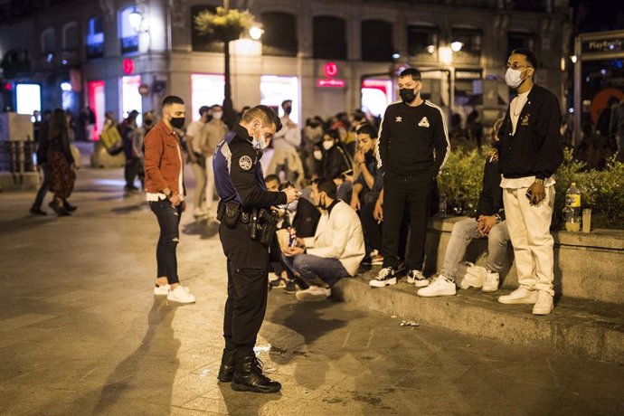 Archivo - Un agente de la Policia Municipal propone para sanción a un grupo de jóvenes por consumir bebidas alcohólicas en la Puerta del Sol. Archivo.