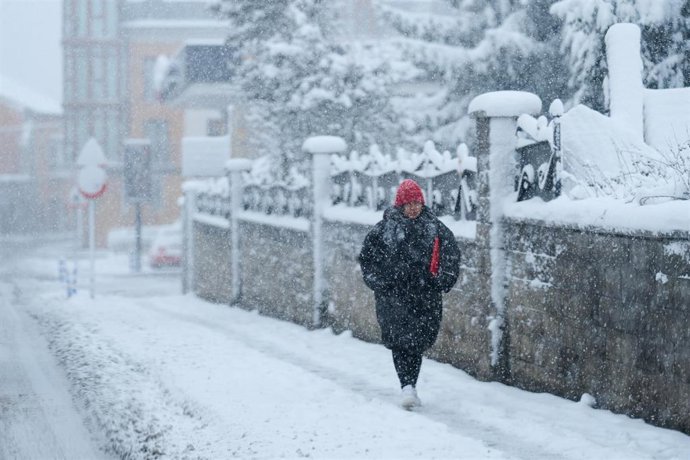 Una mujer camina por la calle mientras nieva, a 18 de enero de 2023, en Cantabria (España).- Archivo