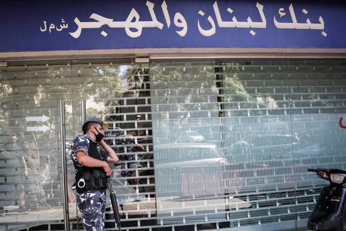 Archivo - Un policía de Líbano ante el escaparate de un banco en la capital, Beirut