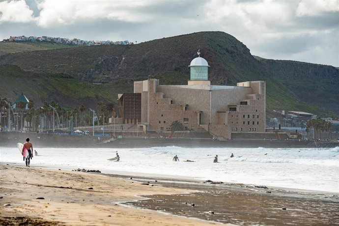 Un surfista pasea por la playa el día más frío del año en la playa de las Canteras, a 21 de enero de 2023, en Las Palmas de Gran Canaria, Las Palmas, Canarias (España). A partir de hoy, las temperaturas descienden por la llegada de una gélida masa de ai