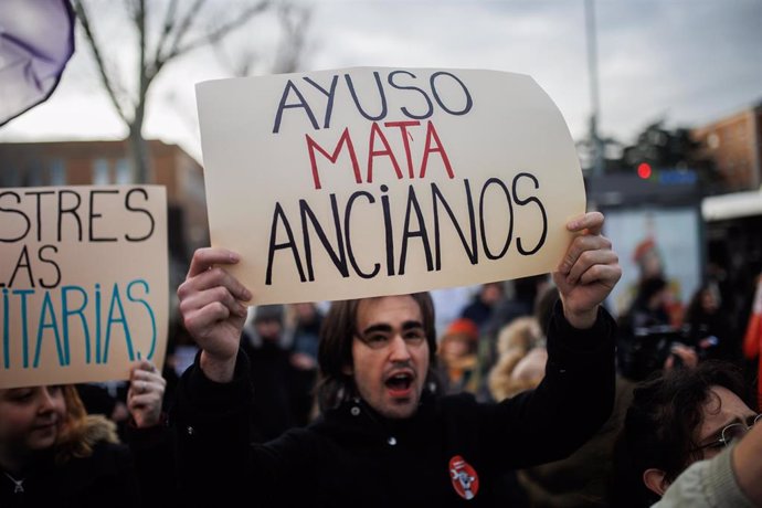 Un hombre con un cartel durante una concentración en contra de la distinción de la presidenta de la Comunidad de Madrid como Alumna Ilustre de la Complutense, en las inmediaciones de la Universidad Complutense, a 24 de enero de 2023, en Madrid (España).