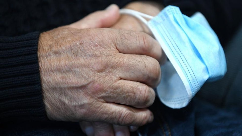 Archivo - Arquivo - Unha persona maior toma unha máscara entre as súas mans