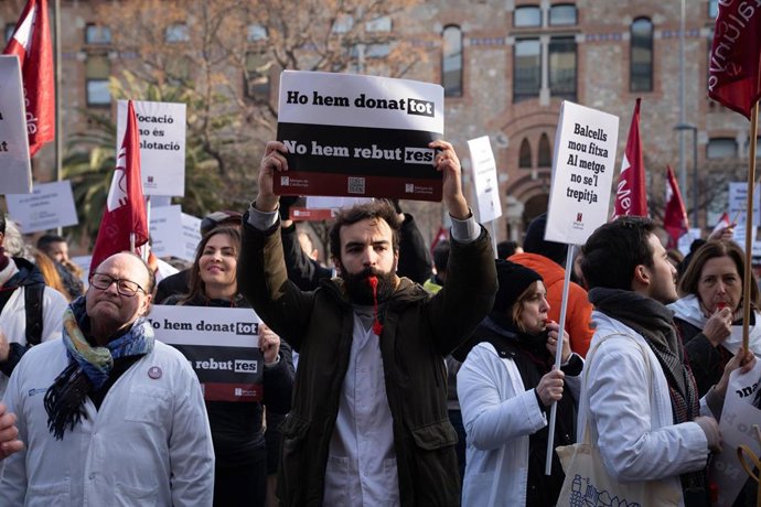 Varias personas protestan con pancartas y batas blancas durante una manifestación del sindicato médico Médicos de Cataluña por la huelga sanitaria, a 25 de enero de 2023, en Barcelona, Cataluña (España). 