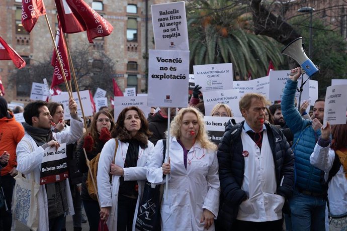 Varias personas protestan con pancartas y batas blancas durante una manifestación del sindicato médico Metges de Catalunya por la huelga sanitaria, a 25 de enero de 2023, en Barcelona