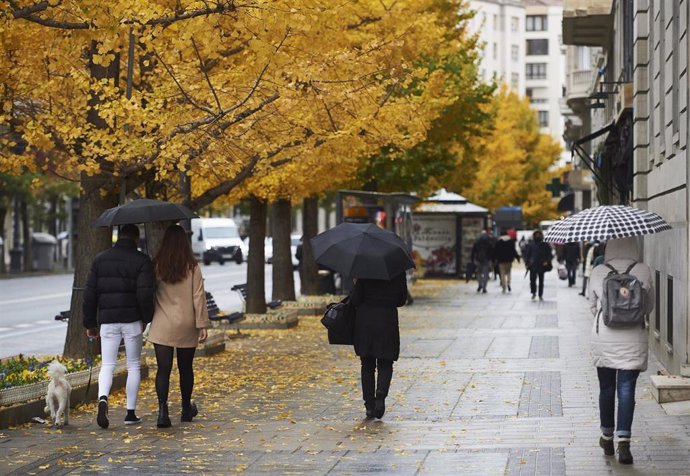 Archivo - Varias personas con paraguas pasean por una calle de Santander