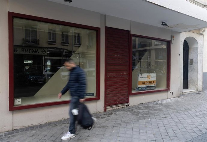 Archivo - Una persona pasa por delante de un comercio cerrado, en Madrid (España)