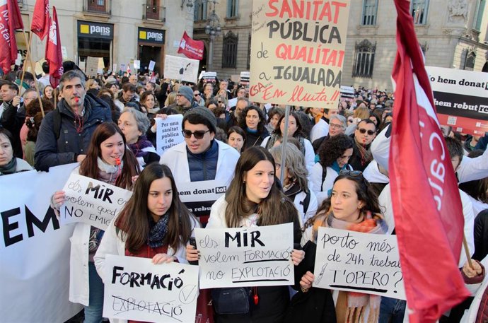 Manifestantes con pancartas y batas blancas durante una concentración de Metges de Catalunya, el segundo día de huelga, a 26 de enero de 2023, en Barcelona