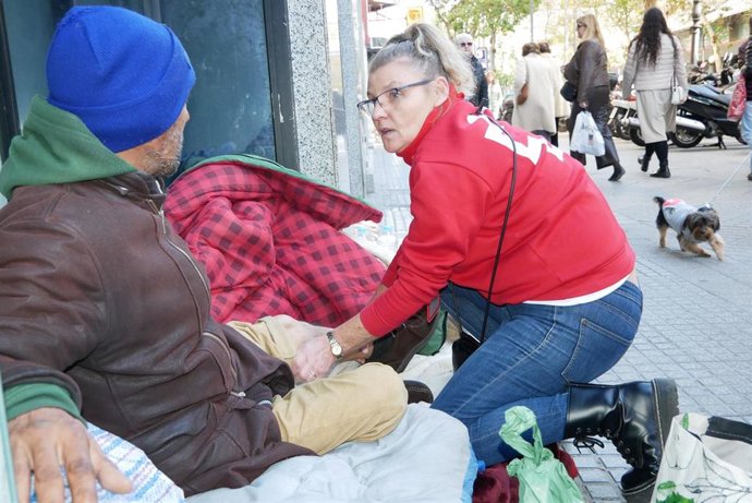 Una voluntaria de Cruz Roja junto a una persona sin hogar.