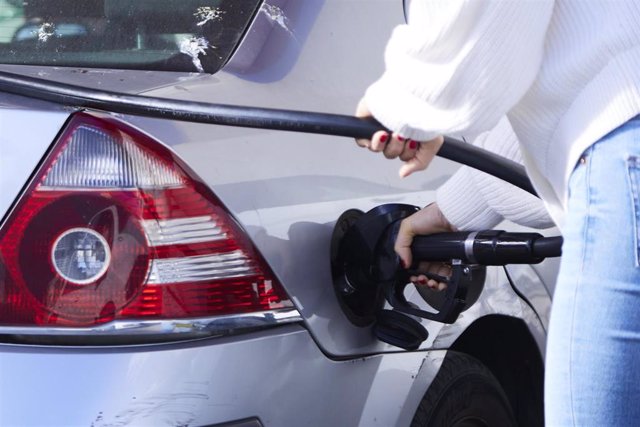 Una mujer echa gasolinera autoservicio a su vehículo.
