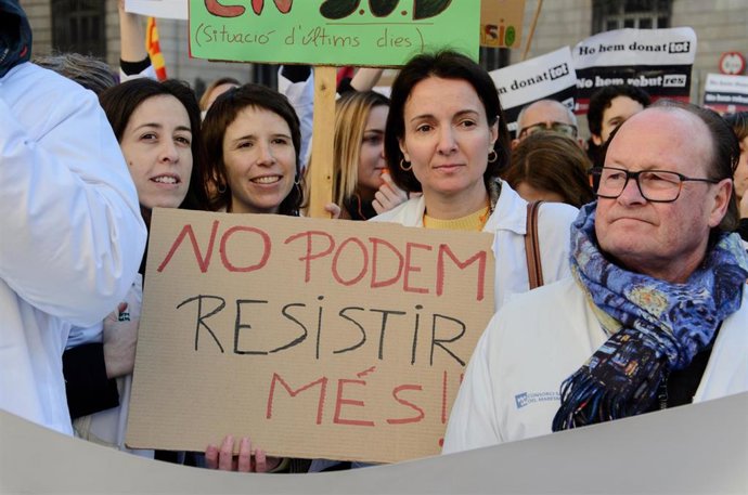 Varias personas protestan con pancartas y batas blancas en la segunda jornada de hulega de facultativos convocada por Metges de Catalunya