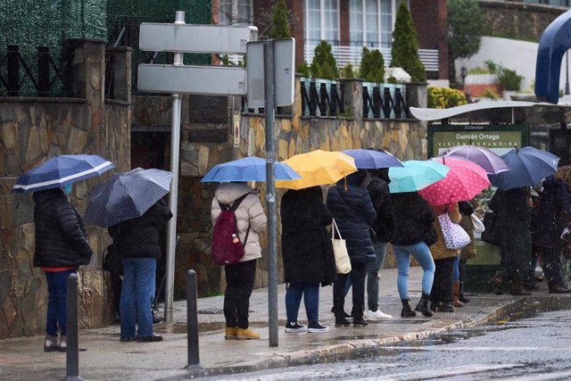 Una fila de personas con paraguas en Santander