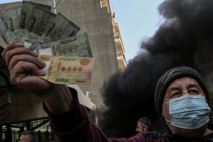 25 January 2023, Lebanon, Beirut: An anti-government Lebanese activist displays Lebanese bills during a protest outside the country's central bank against the continuing downward spiral of the Lebanese pound against the dollar and Riad Salameh's arrest,