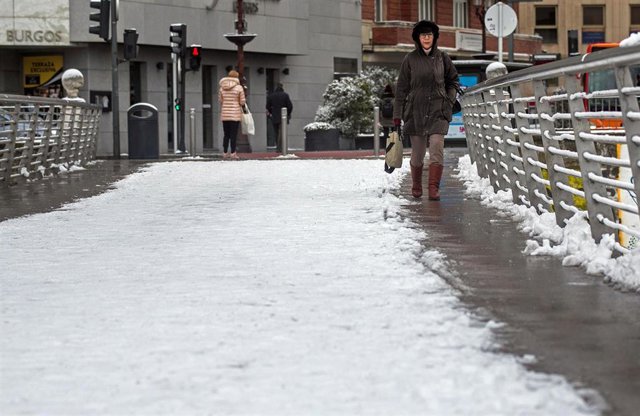 Una mujer camina por una calle cubierta de nieve, a 18 de enero de 2023, en Burgos. Foto de archivo.