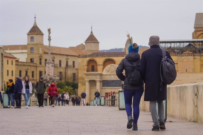 Transeúntes y turistas por el famoso puente de San Rafael con vistas a la Mezquita  en el primer día intenso de frío  a 16 de enero de 2023 en Córdoba (Andalucía, España). 