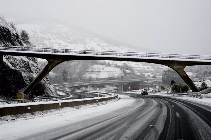 Un coche conduce por una carretera cubierta de nieve en Cantabria. Foto de archivo