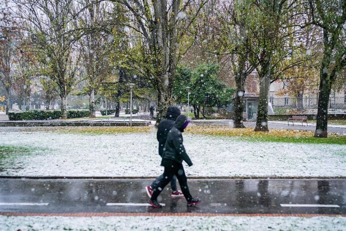 Archivo - Dos personas caminan bajo la nieve en Vitoria, 