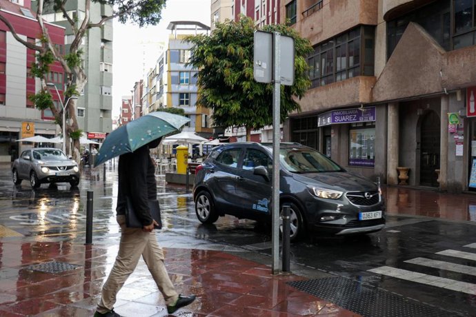 Archivo - Un hombre camina bajo la lluvia en Las Palmas de Gran Canaria