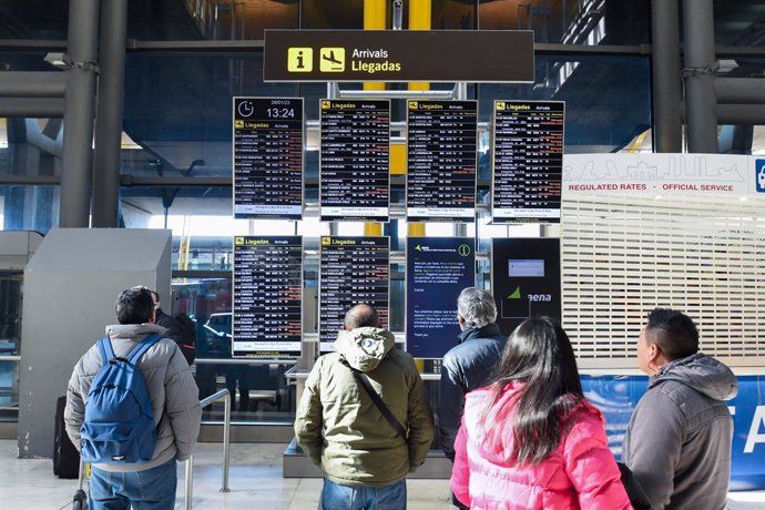 Varias personas observan los paneles informativos que anuncian retrasos de llegadas en algunos vuelos de Iberia en la Terminal 4 del Aeropuerto Madrid-Barajas Adolfo Suárez, a 28 de enero de 2023, en Madrid (España). 