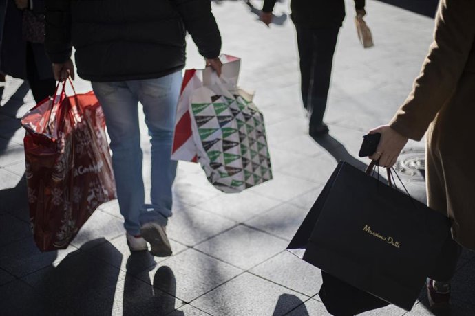 Imagen de archivo de varias personas con bolsas de la compra.