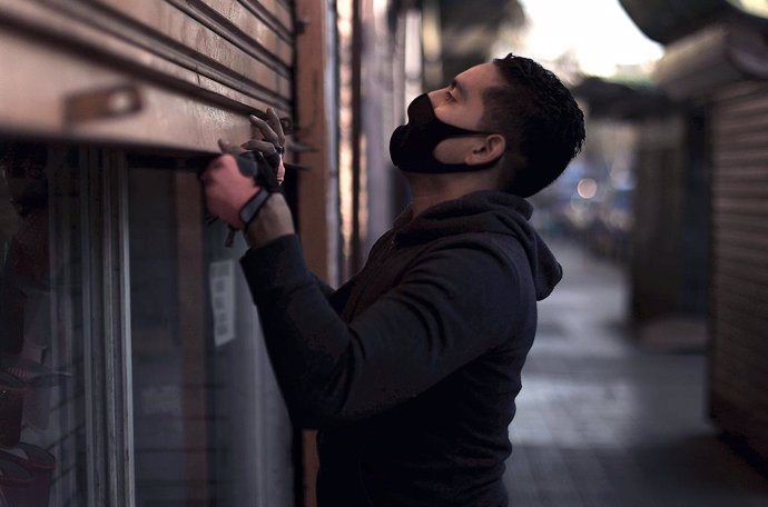 Archivo - Un hombre abre su tienda en Santiago de Chile