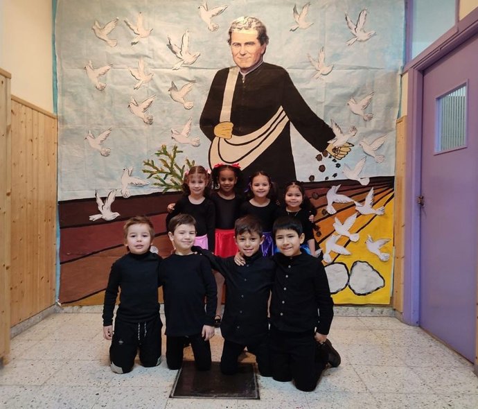 Un grupo de niños junto a la imagen de San Juan Bosco.