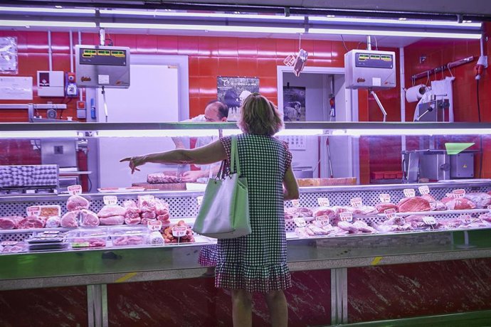 Archivo - Una mujer, frente a un puesto de carne en un mercado municipal.