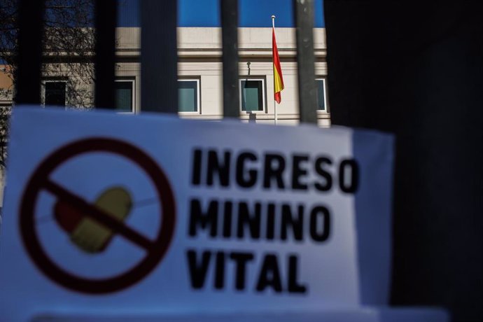 Archivo - Un cartel en el que se lee: 'Ingreso Mínimo Vital' en las rejasl del Ministerio de Inclusión y Seguridad Sociall