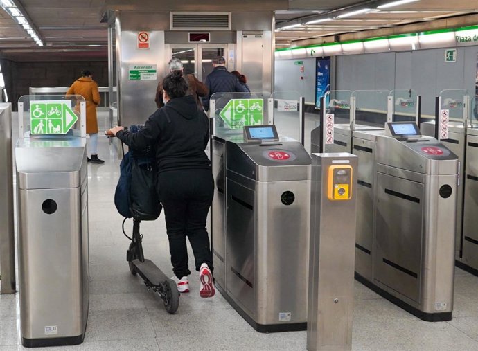 Una usuaria entra con su patinete en el Metro de Sevilla.