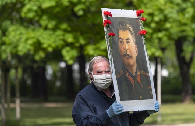 Archivo - Un hombre sostiene un retrato del líder soviético Joseph Stalin.