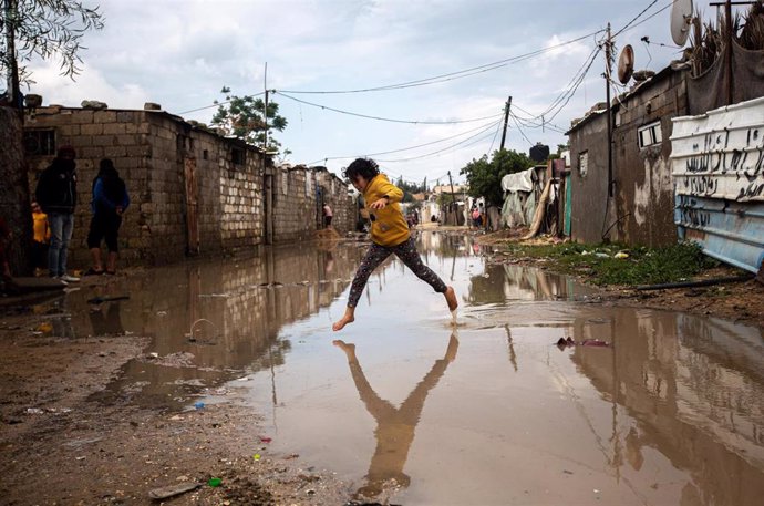 Archivo - Un niño corre por el agua tras unas fuertes lluvias en Jan Yunis, suroeste de la Franja de Gaza