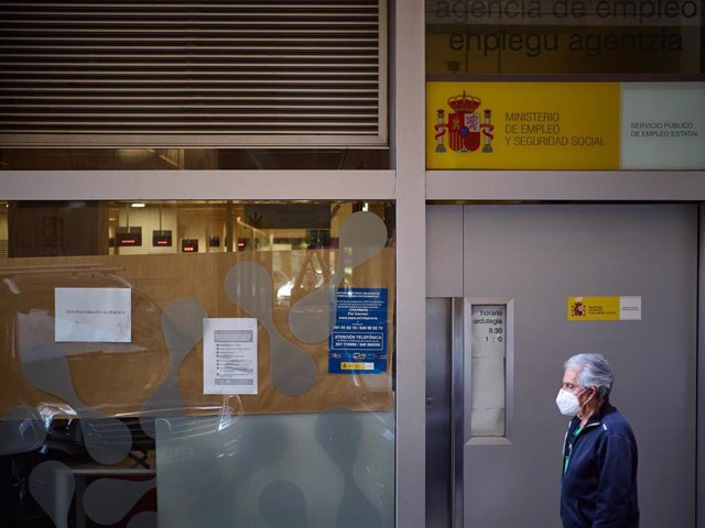 Archivo - Un hombre pasa frente a una oficina de empleo en Pamplona..