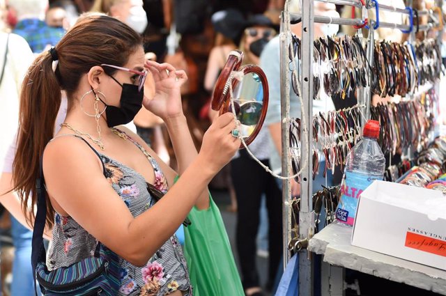 Archivo - Una mujer se prueba unas gafas de sol que se venden en un puesto de El Rastro, a 26 de septiembre de 2021, en Madrid (España). El tradicional mercadillo madrileño de El Rastro vuelve este domingo a la normalidad pre pandemia con el 100 por cient