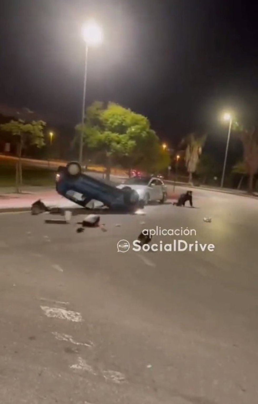 Un vehículo vuelca en una rotonda, con un ocupante sentado en la ventanilla, y choca contra otro coche