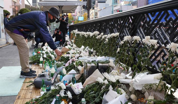 Archivo - Una persona deja flores en un espacio de luto temporal cerca del lugar de la trágica estampida de Halloween en el distrito de Itaewon de Seúl