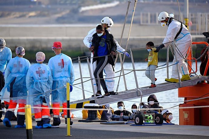 Archivo - Varios trabajadores de Salvamento Marítimo con migrantes rescatados