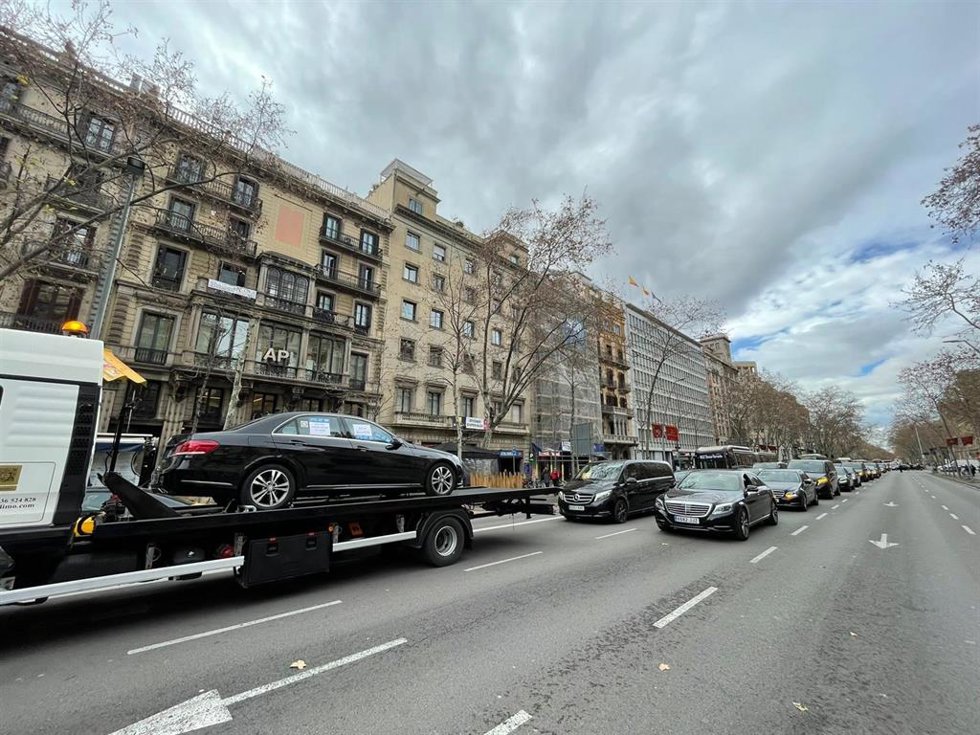 Vehículos de VTC tradicionales se reivindican en una marcha lenta este lunes por Barcelona, liderados por una grúa con un coche de VTC encima