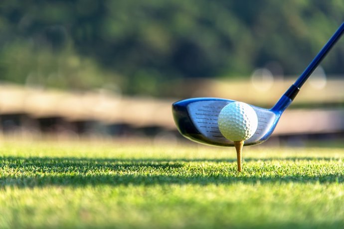 Archivo - Close up golf ball and driver, player doing golf swing tee off on the green sunset evening time, presumably does exercise.  Healthy and Lifestyle Concept.