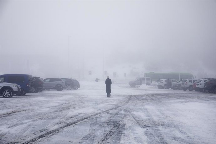 Una persona camina por la nieve en el parking del Puerto de Navacerrada, a 19 de enero de 2023, en Navacerrada, Madrid (España). La Agencia de Seguridad y Emergencias de la Comunidad de Madrid (ASEM 112) ha activado la situación 0 de la fase de alerta d