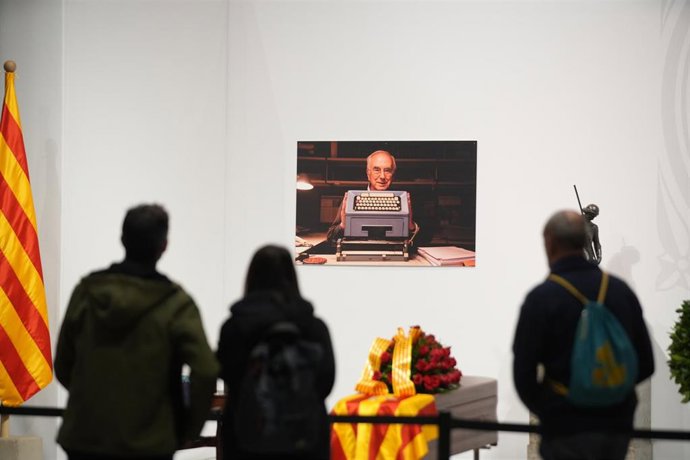 Varias personas delante del féretro del escritor Josep Maria Espins cuando ha abierto la capilla ardiente para los ciudadanos, en el Palau de la Generalitat, a 7 de febrero de 2023, en Barcelona, Catalunya (España).