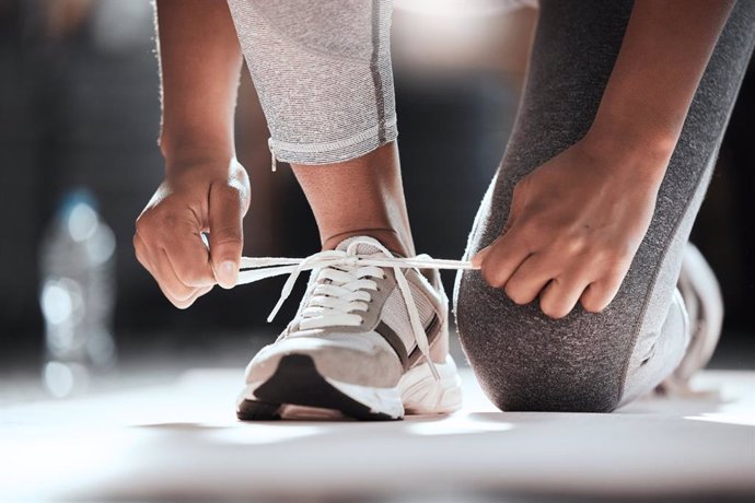 Archivo - Mujer atándose las zapatillas de deporte.