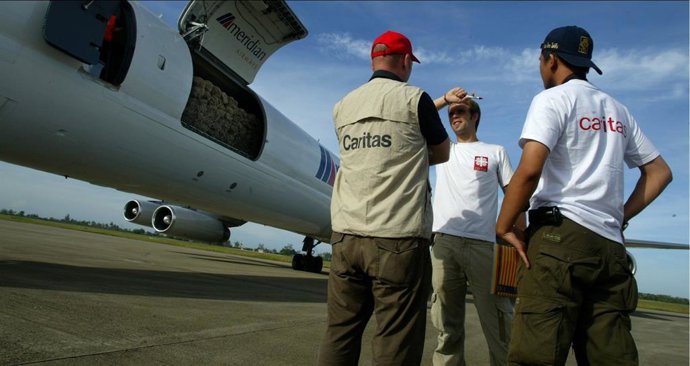 Cooperantes de Cáritas junto a un avión.