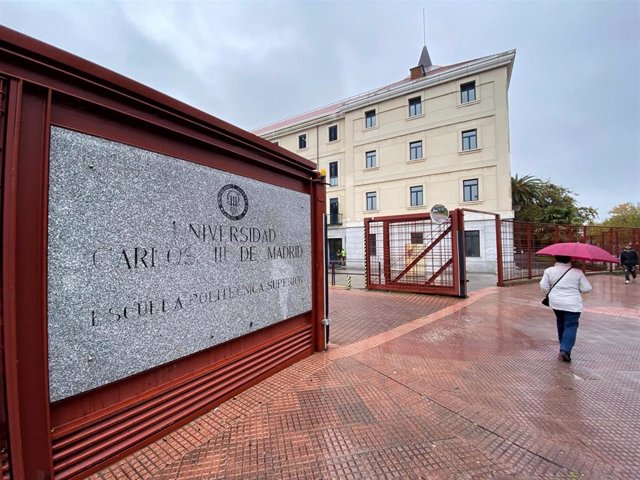 Archivo - Una mujer con paraguas pasa junto a la placa y la entrada a la Escuela Politécnica Superior del campus de Leganés de la Universidad Carlos III de Madrid,