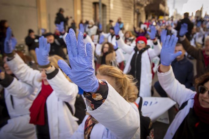 Varias personas con batas blancas y guantes azules protestan durante una marcha convocada por médicos y pediatras de Atención Primaria