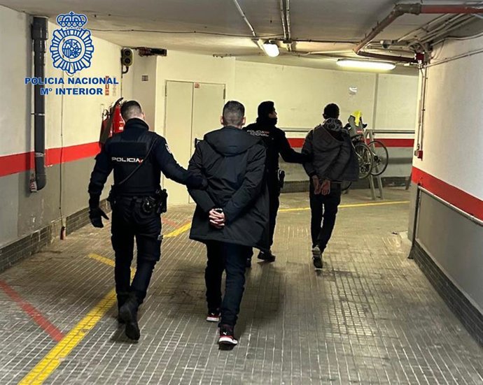 Dos agentes de la Policía Nacional llevan a los detenidos.